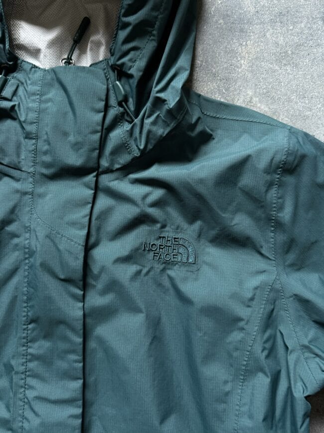Teal North Face jacket with embroidered logo on the left chest