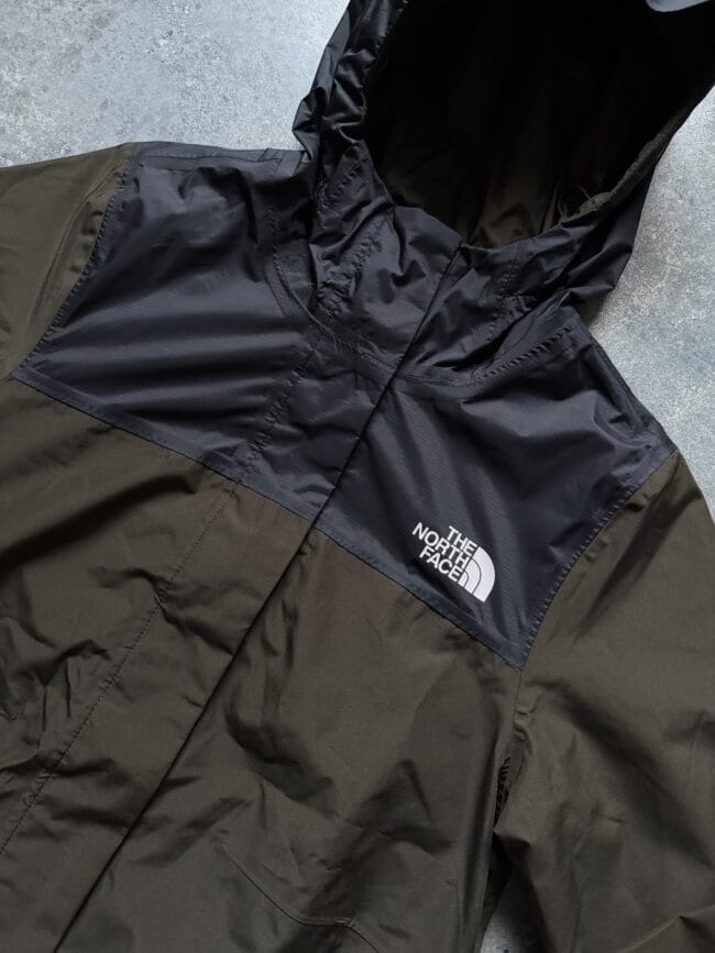 Close-up of a two-tone black North Face jacket with a hood and visible logo on the chest area