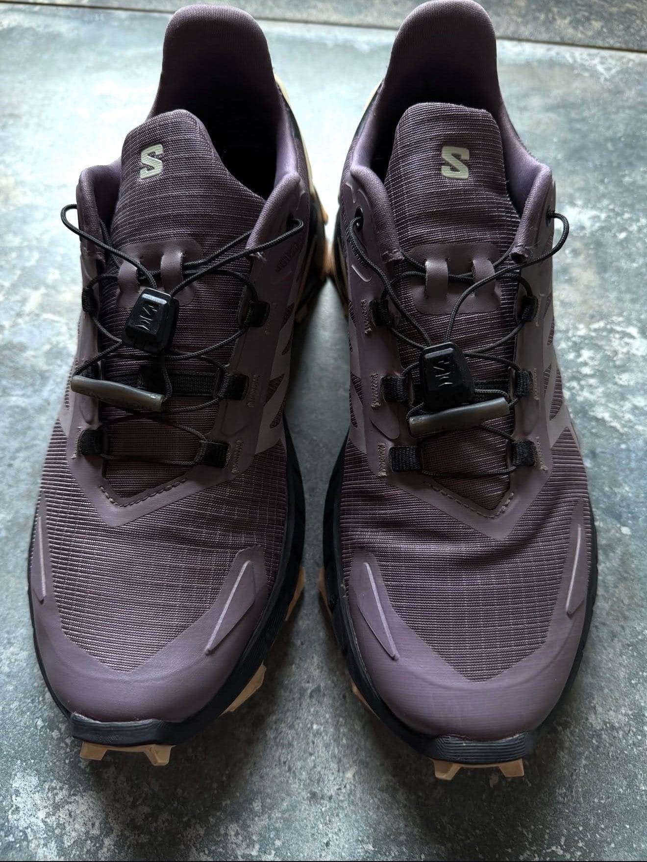 Top-down view of two maroon Salomon hiking shoes with black laces and rugged tan outsoles.