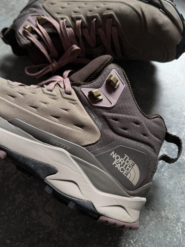 Close-up of a brown hiking boot showing purple laces and rugged sole, with The North Face branding visible on the side.