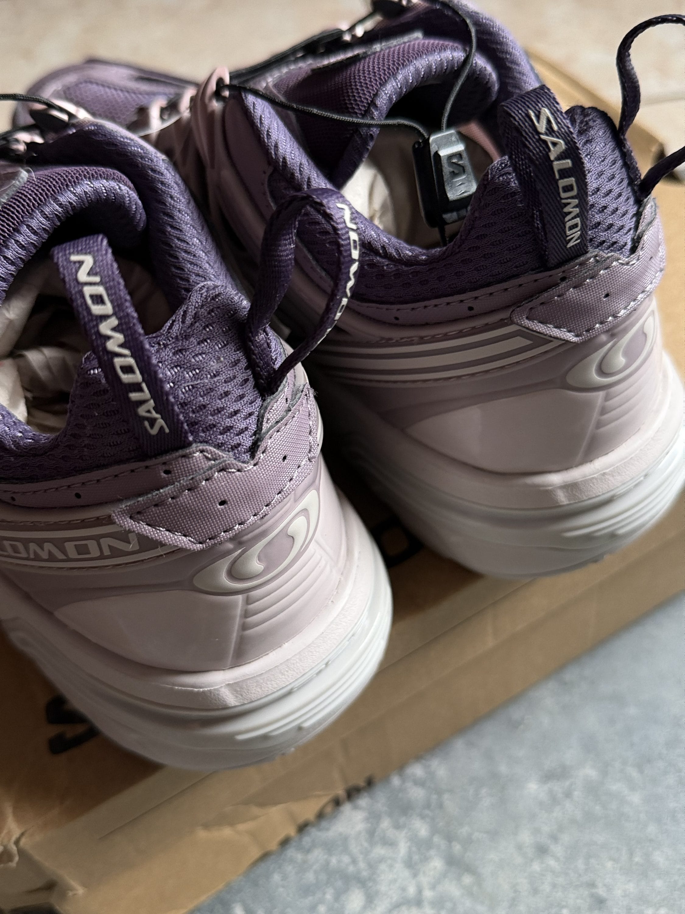 Close-up of two purple athletic sneakers with padded mesh uppers, laces, and thick white soles visible from the back/top.