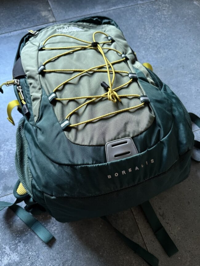 Olive-green backpack with yellow elastic bungee cords crisscrossing the front and the 'BOREALIS' logo visible on the pocket.