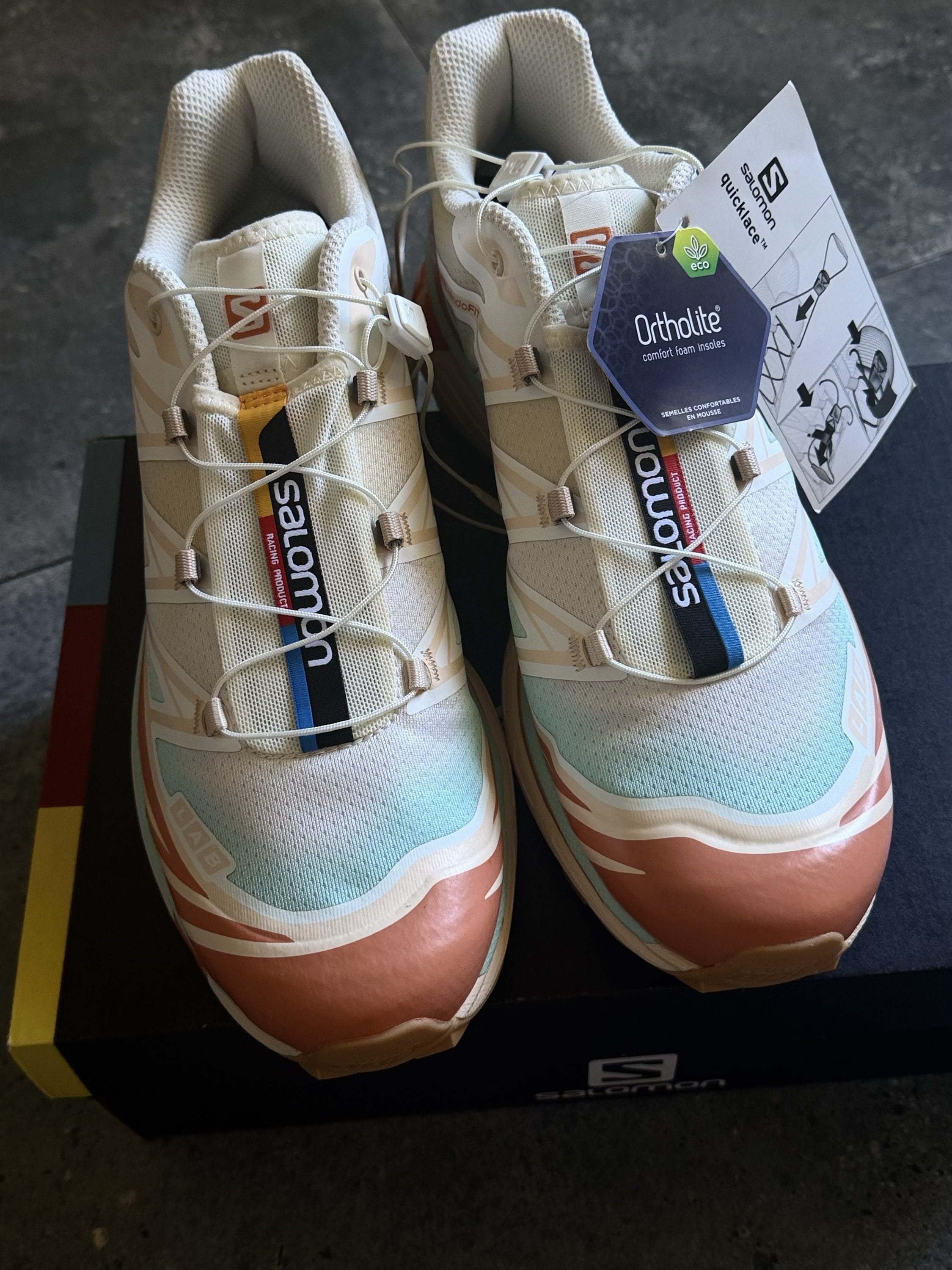 Pair of light-colored Salomon running shoes with laces and Ortholite tag attached.