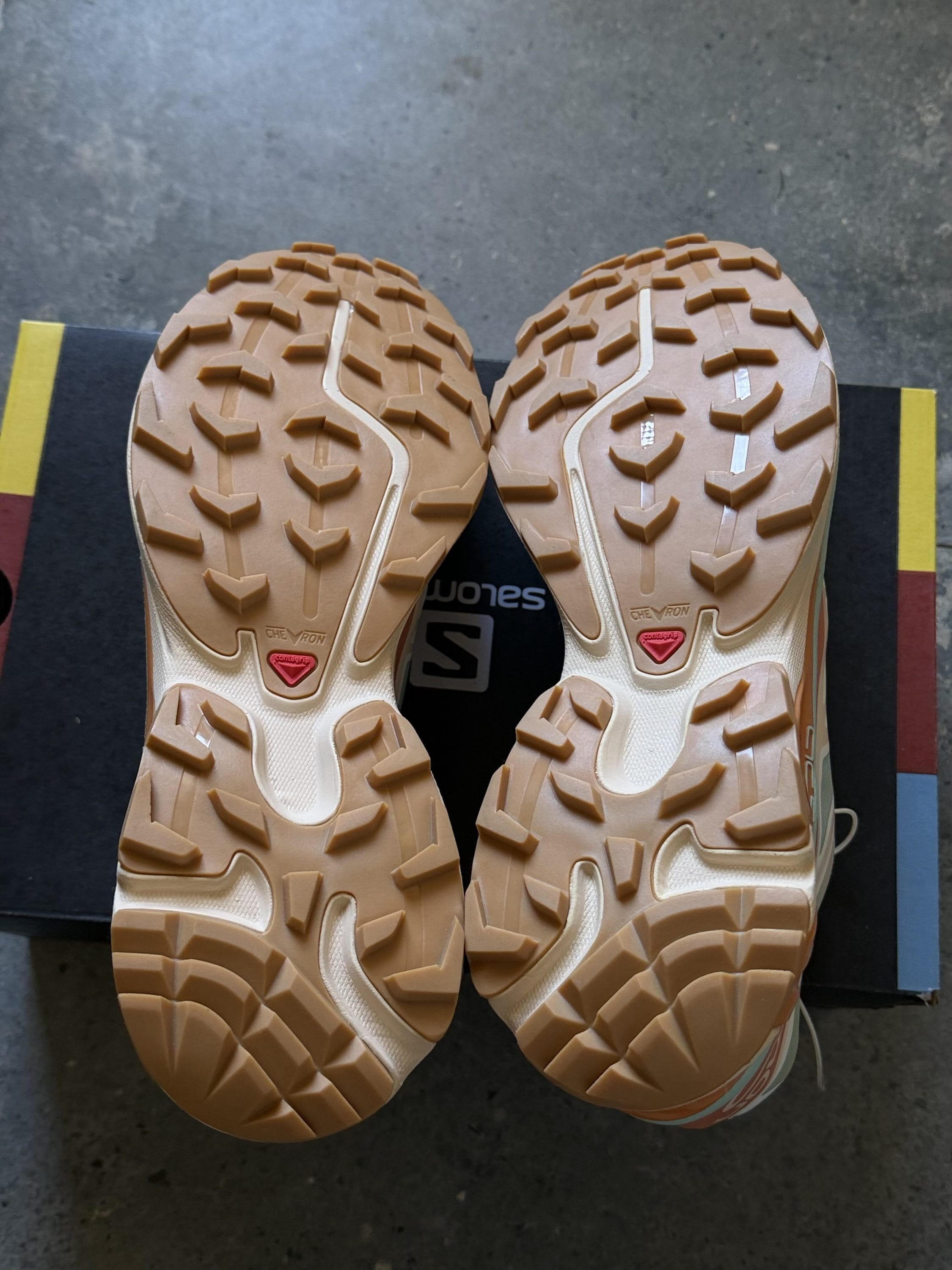 Pair of beige hiking shoes viewed from above, showing rugged tan tread aggressively gripping the ground.