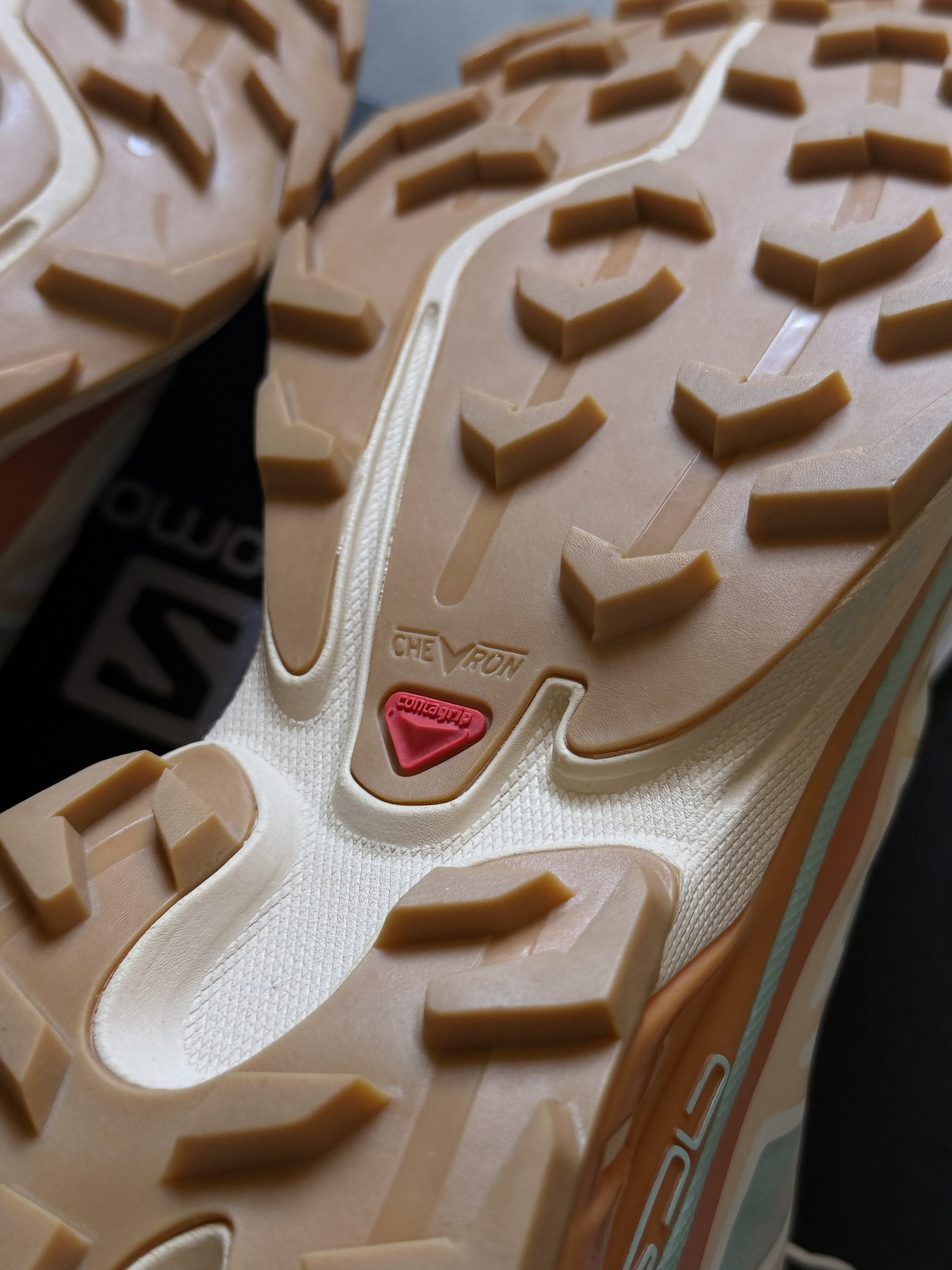 Close-up of a tan hiking shoe outsole with chunky rectangular lugs and a red heel tab.