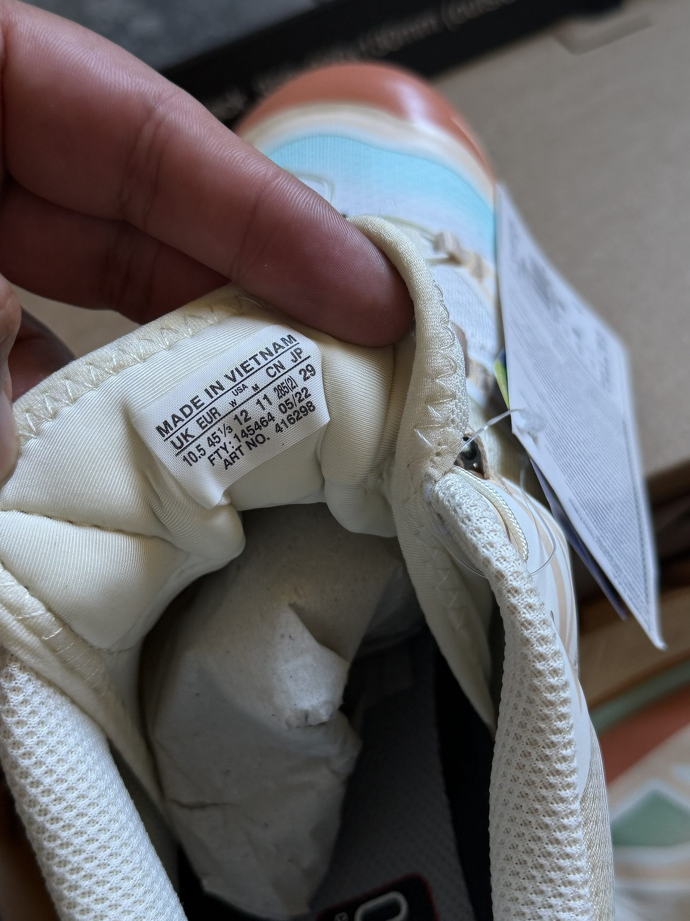Inside of a beige sneaker showing the size and origin tag (Made in Vietnam) on the inner tongue area.
