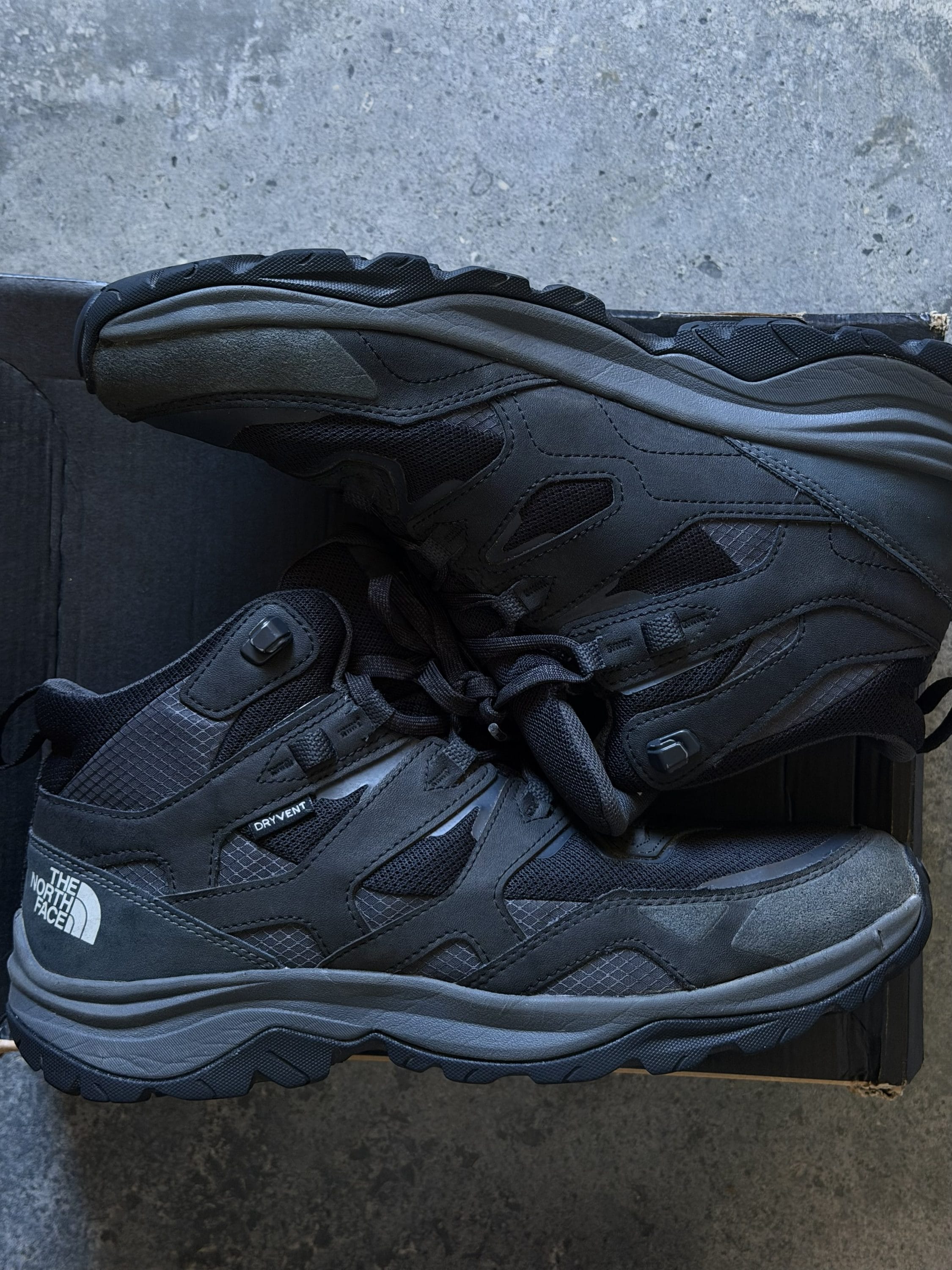 Black The North Face hiking boot with rugged lug sole resting on a concrete surface