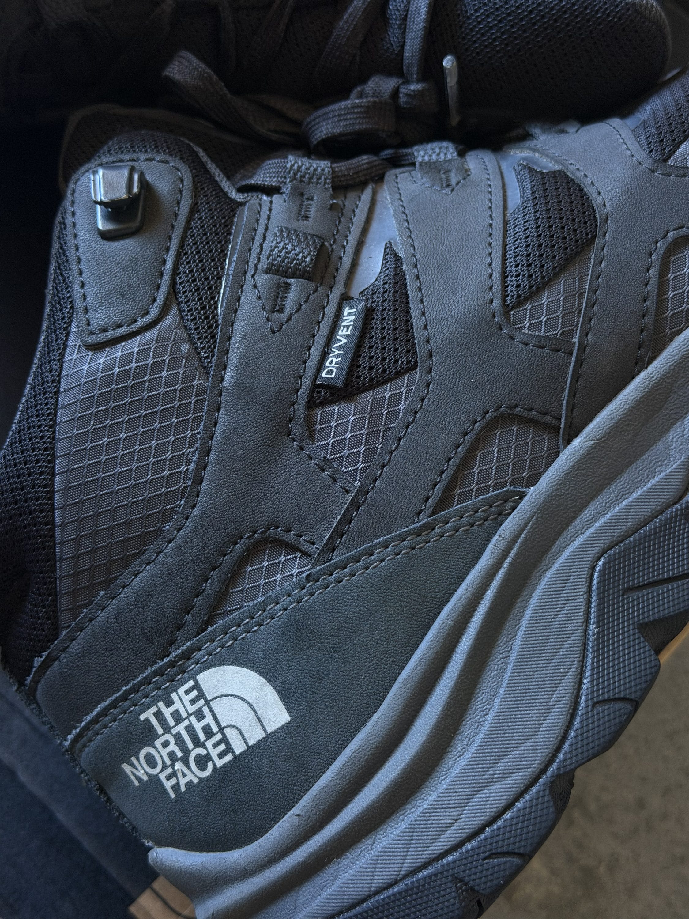 Close-up of a black The North Face hiking boot, showing mesh panels, laces, and rugged sole details.